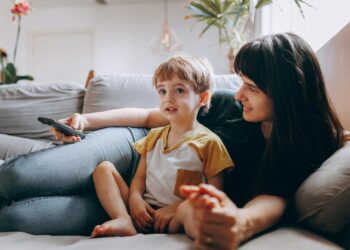 A mother and son spending quality time watching TV on a cozy couch at home.