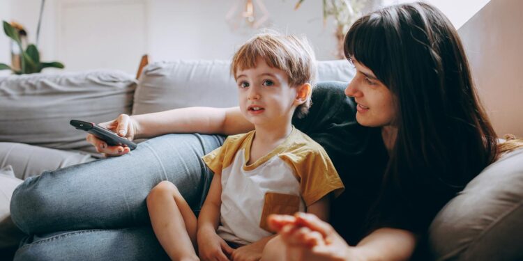 A mother and son spending quality time watching TV on a cozy couch at home.