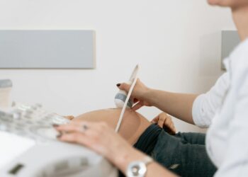 A healthcare professional performs an ultrasound on a pregnant woman in a clinic.
