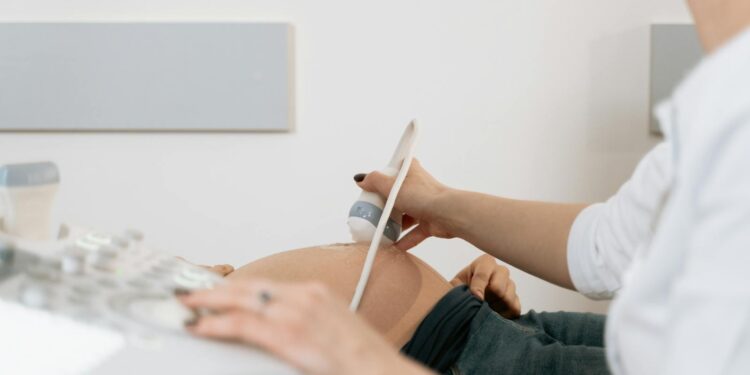 A healthcare professional performs an ultrasound on a pregnant woman in a clinic.