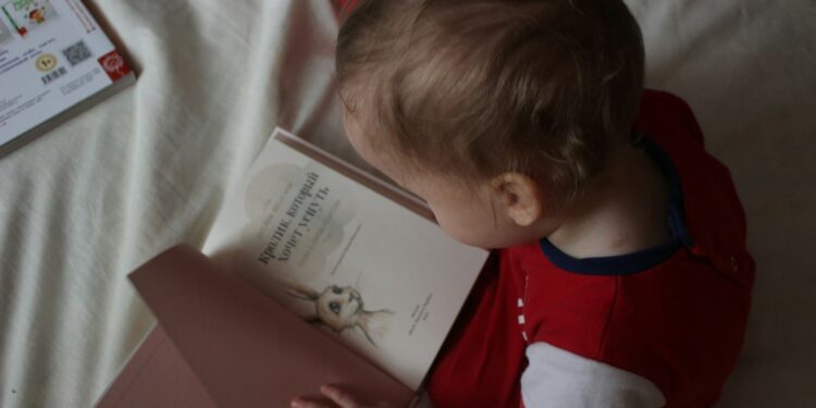 baby sitting on bed while reading on book