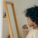 Young child with curly hair brushing teeth in front of mirror, emphasizing morning routine and hygiene.